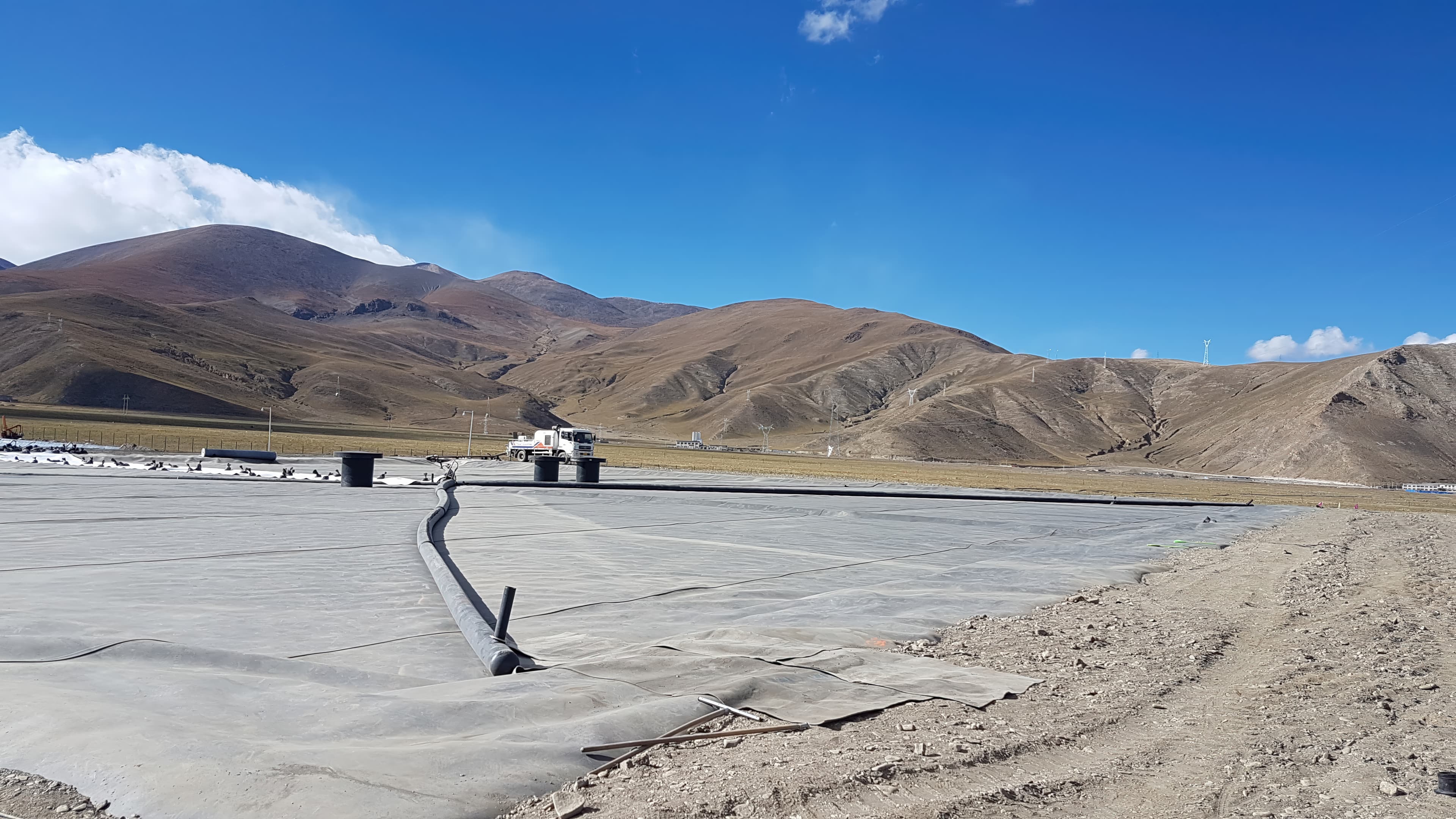 A light-grey GSE HD 1.5 mm geomembrane forms the top cover, combining UV resistance with low heat absorption to protect the lid’s insulation and structure.