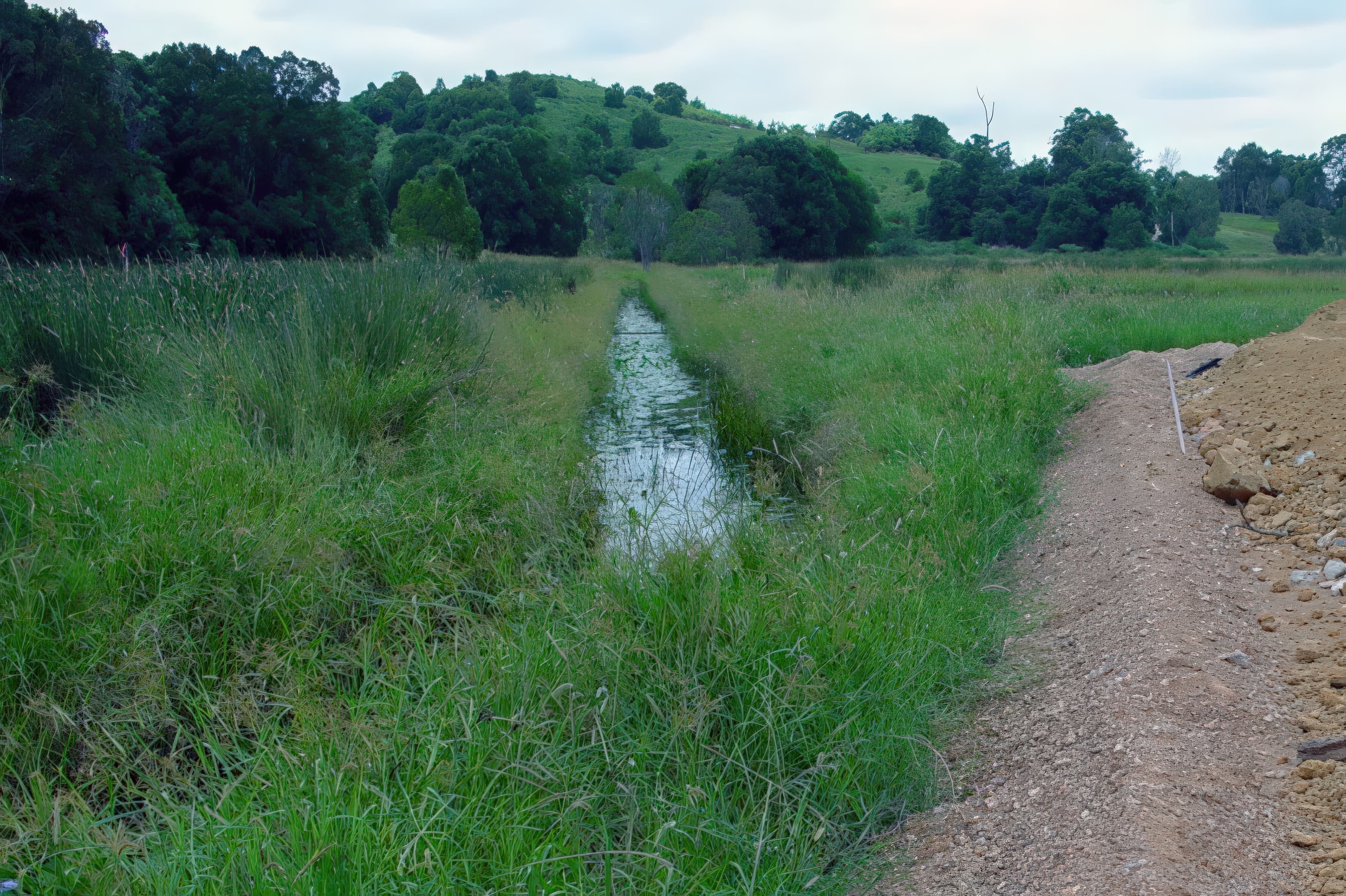 High-strength woven geotextiles were installed across the drainage layer with 0.5 m overlaps, followed by placement of variable fill and a 1 m surcharge to accelerate foundation consolidation.