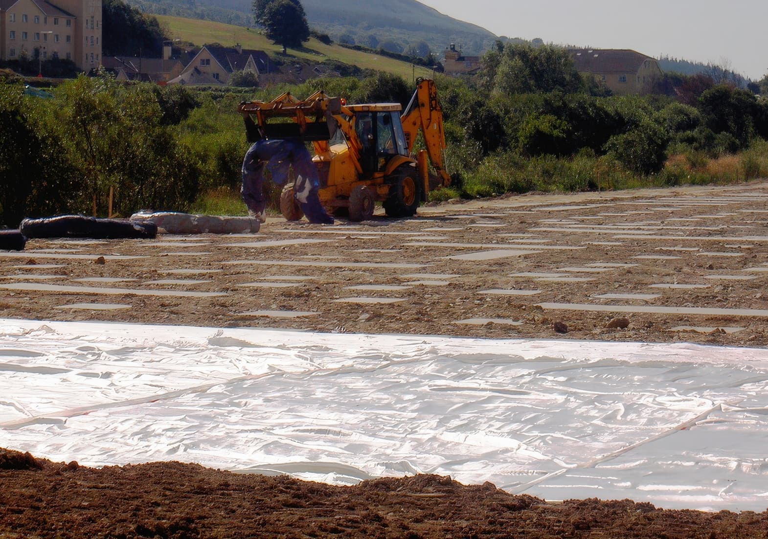 Laying MIRAFI Geolon PET geotextile reinforcement across the top of the pile caps