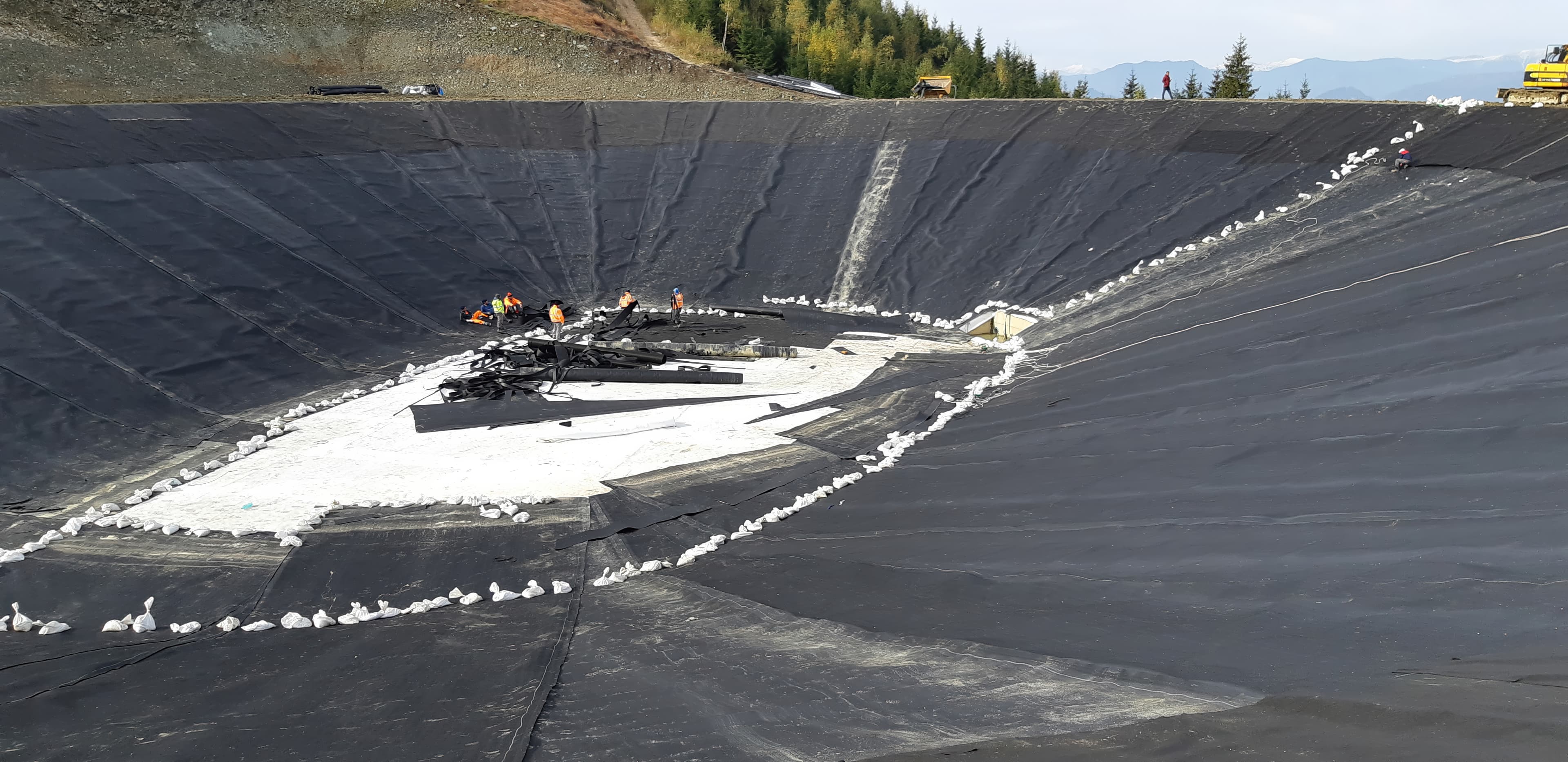 Installation of gravel, triaxial geogrid, and geocells on the lake slopes to provide drainage, confinement, and reinforcement.