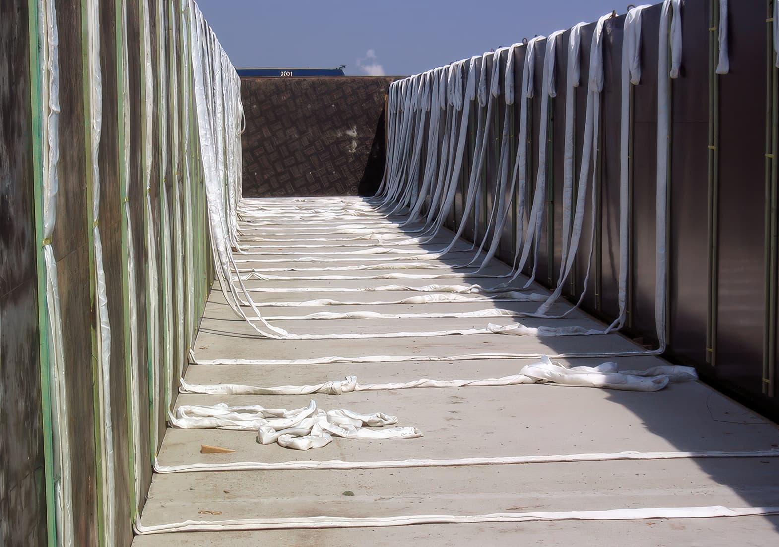 Large sand-cement block facings with attached MIRAFI Geolon PET200 geotextile were lifted by floating crane and installed to reinforce the dam’s outer slope.