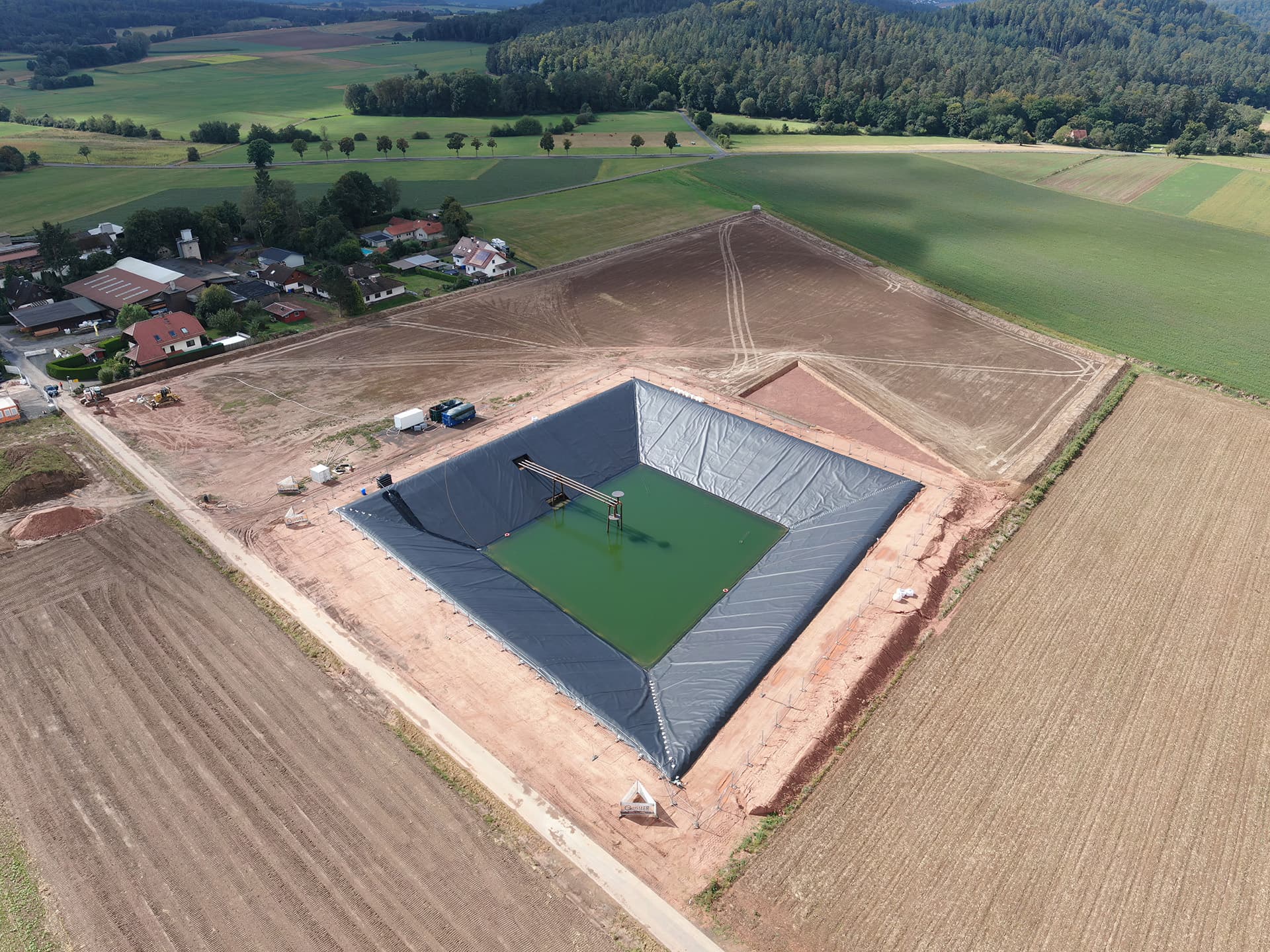 The completed Bracht PTES integrates solar collectors, heat pumps, and a biomass boiler, demonstrating how geosynthetics enable safe, scalable seasonal heat storage for fossil-free districts.