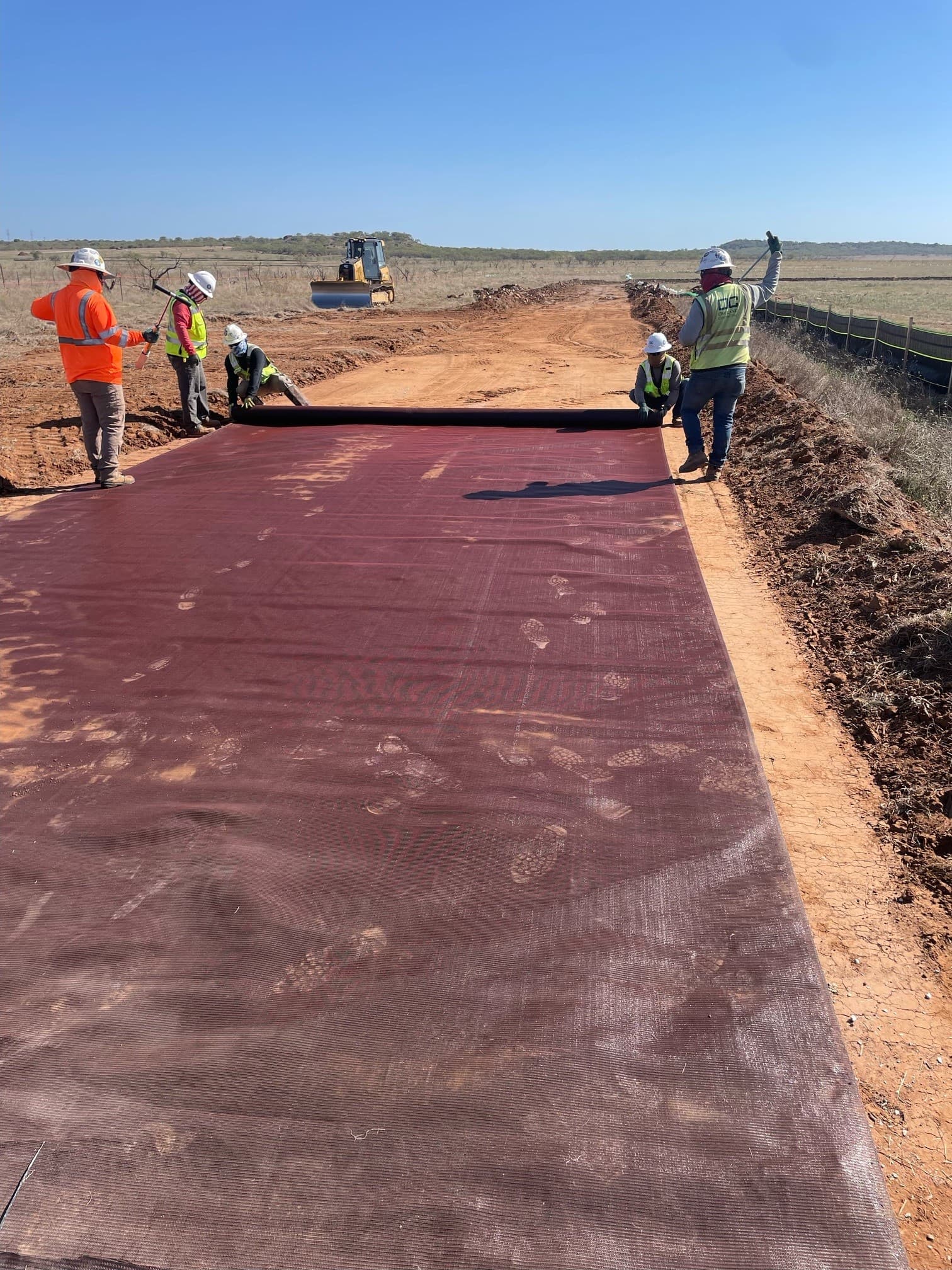 Geotextile reinforcement installed to reduce base thickness for solar farm roads.