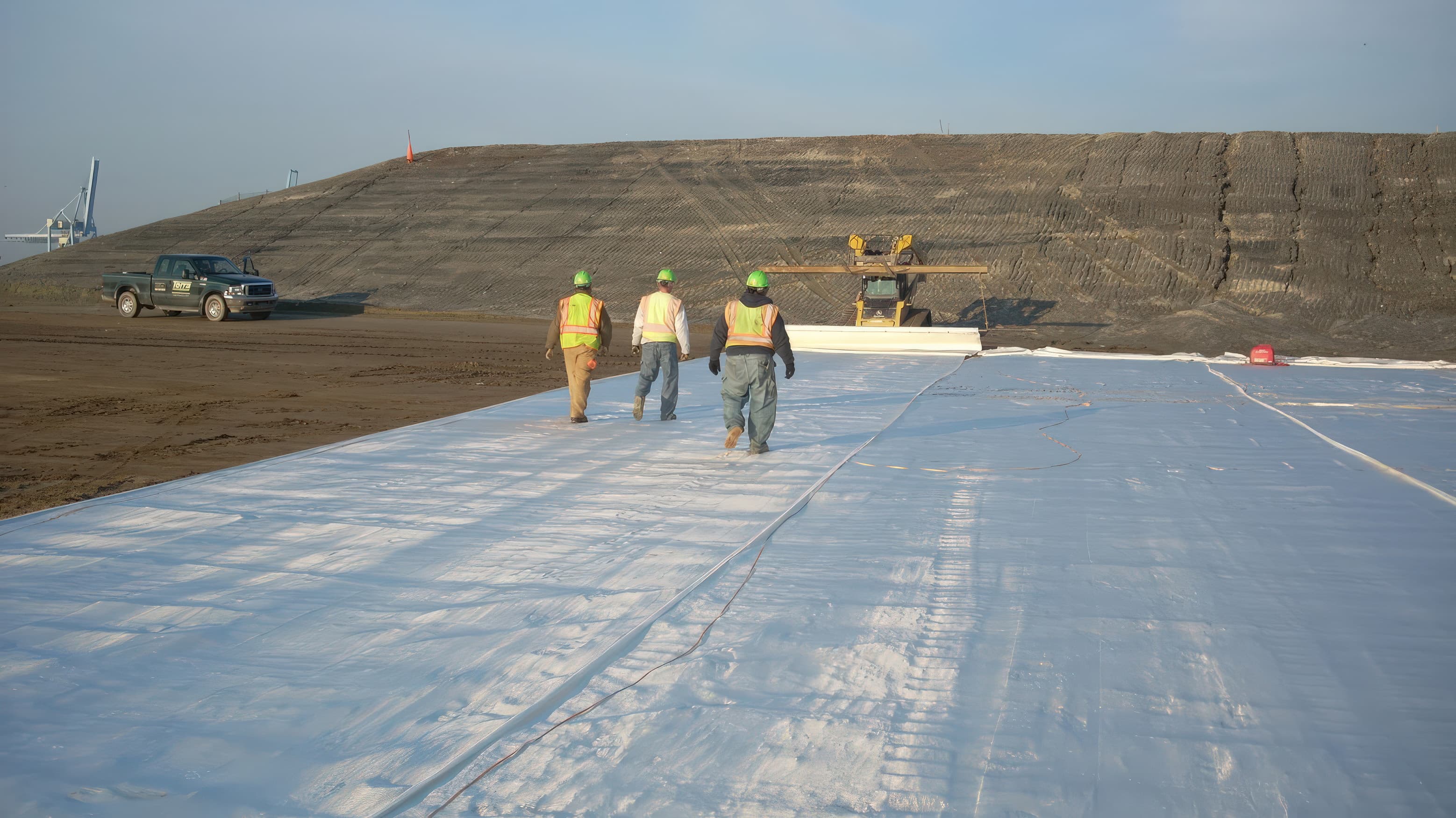 Installation workers walking across a newly rolled out geotextile.
