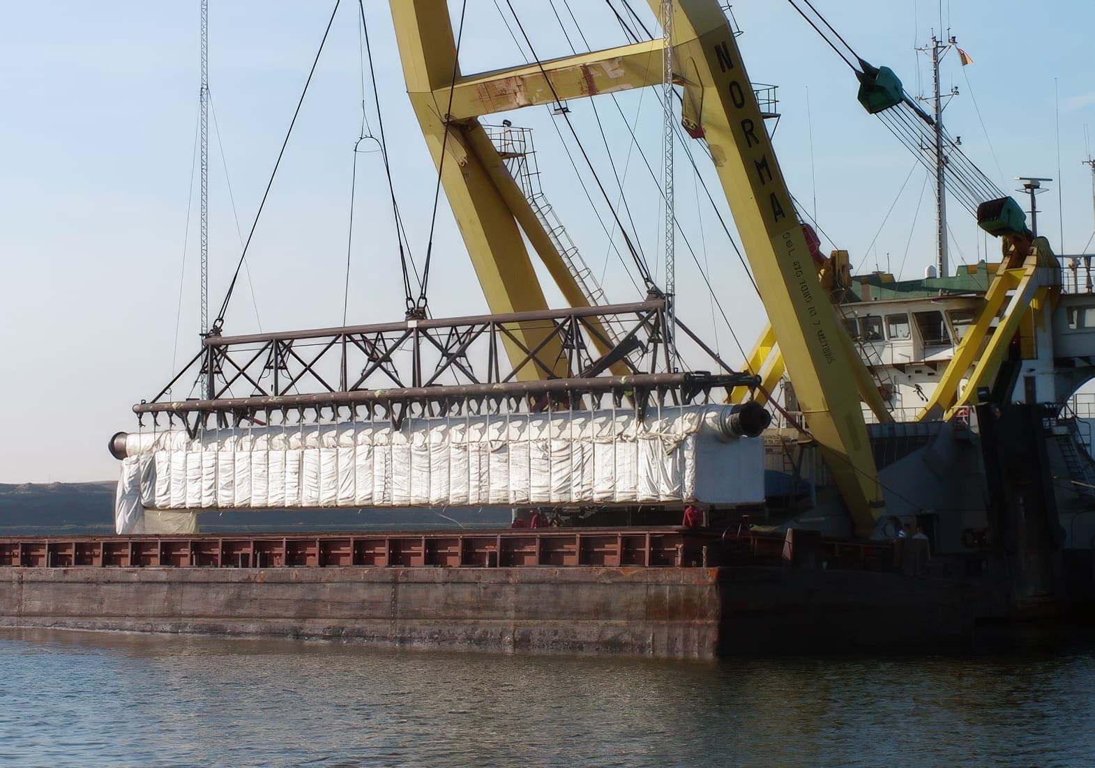 Eight layers of PET200 geotextile, spaced at 2 m intervals and extending up to 100 m, were rolled out underwater to provide shear stability during fill placement.