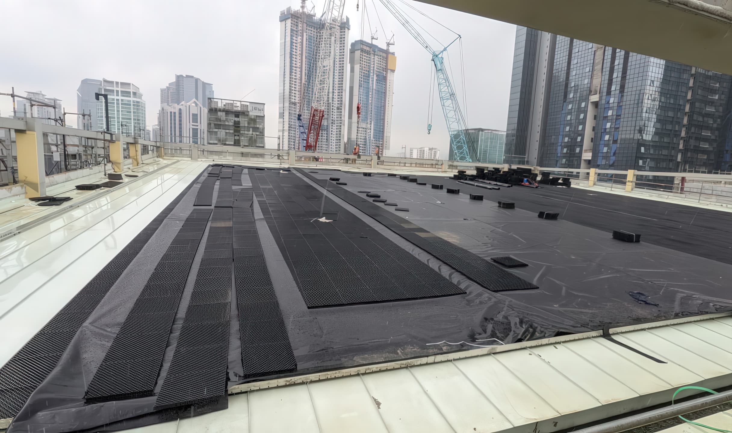 Installing a smooth GSE HD geomembrane as the primary roof barrier layer for a green roof system.